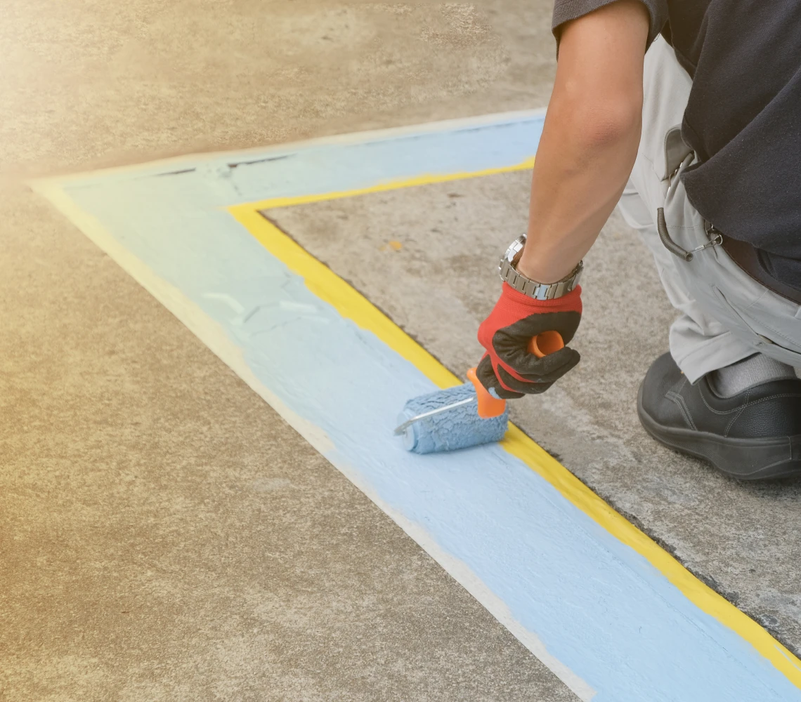 Man painting yellow-bordered area on ground